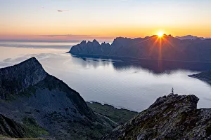 Person admiring the fjord at dawn standing on top of Husfjellet mountain, Senja island Person admiring the fjord at dawn standing on top of Husfjellet mountain, Senja island