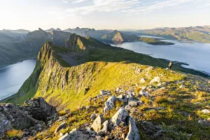 Person hiking on Husfjellet mountain at dawn, Senja island, Troms county, Norway Person hiking on Husfjellet mountain at dawn, Senja island, Troms county, Norway