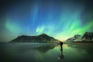 Person photographing the bright sky during Aurora Borealis (Northern Lights) standing on Skagsanden beach