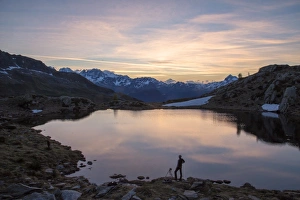 Photographer admires the pink sunrise on Lake Zana, Malenco Valley, Valtellina, Province of Sondrio Photographer admires the pink sunrise on Lake Zana, Malenco Valley, Valtellina, Province of Sondrio