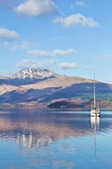 Picturesque tranquil Loch Lomond with sailing boat, snow covered Beinn Uird behind Picturesque tranquil Loch Lomond with sailing boat, snow covered Beinn Uird behind