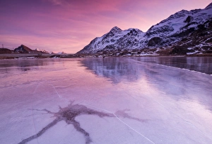 Pink sky at sunset on the frozen Lej Nair framed by snowy peaks, Bernina Pass, Canton of Graubunden Pink sky at sunset on the frozen Lej Nair framed by snowy peaks, Bernina Pass, Canton of Graubunden
