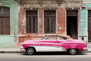 A pink and white vintage American convertible car parked on a street in Havana, Cuba A pink and white vintage American convertible car parked on a street in Havana, Cuba