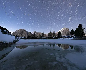 Polar star trail in the night sky over Lagazuoi and Tofana di Rozes peaks from frozen Polar star trail in the night sky over Lagazuoi and Tofana di Rozes peaks from frozen