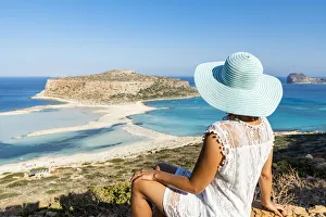 Portrait of woman with hat admiring the idyllic beach and lagoon sitting on top of hill Portrait of woman with hat admiring the idyllic beach and lagoon sitting on top of hill