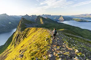 Rear view of man walking on path to Husfjellet mountain peak at sunrise, Senja island Rear view of man walking on path to Husfjellet mountain peak at sunrise, Senja island
