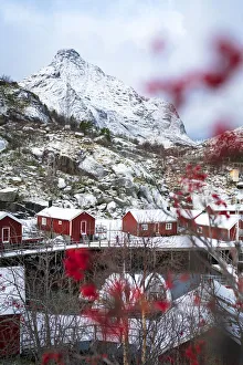 Red Rorbu cabins framed by snowcapped mountains in winter, Nusfjord, Nordland county, Lofoten Islands, Norway Red Rorbu cabins framed by snowcapped mountains in winter, Nusfjord, Nordland county, Lofoten Islands, Norway