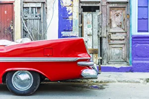 A red vintage car parked against colourful local architecture in Havana, Cuba, West Indies A red vintage car parked against colourful local architecture in Havana, Cuba, West Indies