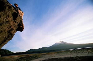 Rock climber attempts bouldering, and volcano in background, Conguillio National Park