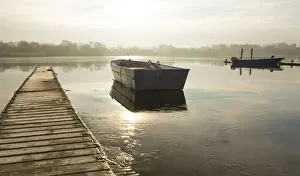 East Yorkshire Gallery: A rowing boat floats adrift on a frozen lake beside an empty walkway at Hornsea Mere