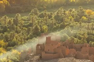 Images Dated 15th November 2014: Ruined kasbah in the palmerie near Tinerhir, with smoke from fire swirling through the palm trees