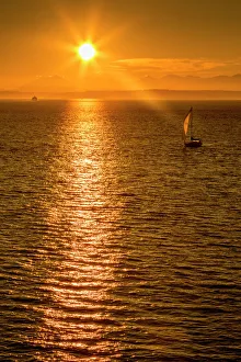 Sailing boat and sunset over Elliott Bay with Bainbridge Island visible on the horizon Sailing boat and sunset over Elliott Bay with Bainbridge Island visible on the horizon