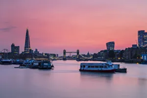 The Shard, Tower Bridge and City of London skyline with river boats on the River Thames at sunset, London, England The Shard, Tower Bridge and City of London skyline with river boats on the River Thames at sunset, London, England
