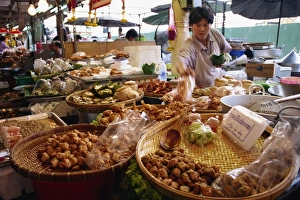 A shopkeeper puts fish cakes on a tray on a stall in A shopkeeper puts fish cakes on a tray on a stall in