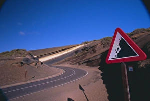 Sign on a road with volcanic stratified rocks in the background Sign on a road with volcanic stratified rocks in the background