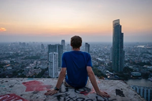 A single man watching sun set over city skyline at dusk, Bangkok, Thailand, Southeast Asia A single man watching sun set over city skyline at dusk, Bangkok, Thailand, Southeast Asia