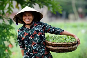 Smiling Vietnamese woman wearing the traditional palm leaf conical hat, Hoi An, Vietnam