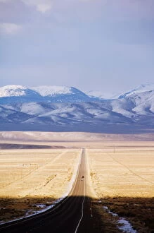 Empty Gallery: Snow capped mountains on a straight road of American south west, U