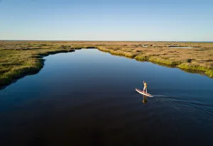 Stand up paddle boarder paddles through a Chesapeake Bay salt marsh near Hampton Stand up paddle boarder paddles through a Chesapeake Bay salt marsh near Hampton