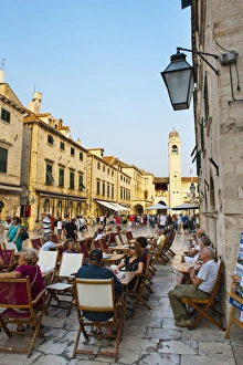 Stradun, the famous street in Dubrovnik, tourists in a cafe by the City Bell Tower Stradun, the famous street in Dubrovnik, tourists in a cafe by the City Bell Tower