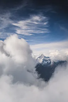 Sunlight over Weisshorn peak emerging from a sea of clouds, canton of Valais, Switzerland Sunlight over Weisshorn peak emerging from a sea of clouds, canton of Valais, Switzerland