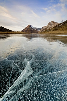 Sunset on the frozen Lej Nair surrounded by rocky peaks, Bernina Pass, Canton of Graubunden Sunset on the frozen Lej Nair surrounded by rocky peaks, Bernina Pass, Canton of Graubunden