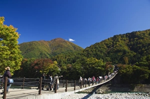 Suspension bridge with tourists looking at autumn colours Suspension bridge with tourists looking at autumn colours