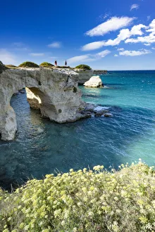 Tourists admiring the sea from natural stone arch on cliff, Torre Sant'Andrea Tourists admiring the sea from natural stone arch on cliff, Torre Sant'Andrea