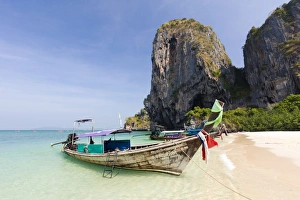 Traditional Longtail boats moored by Phra Nanag Beach with limestone cliffs in the background Traditional Longtail boats moored by Phra Nanag Beach with limestone cliffs in the background
