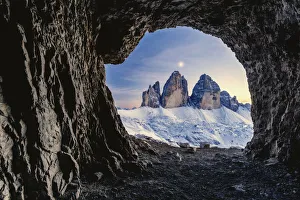 Tre Cime di Lavaredo lit by moon seen from opening in rocks of a war cave Tre Cime di Lavaredo lit by moon seen from opening in rocks of a war cave
