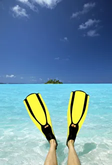 Tropical island and person wearing flippers sitting in sea, Maldives, Indian Ocean, Asia Tropical island and person wearing flippers sitting in sea, Maldives, Indian Ocean, Asia
