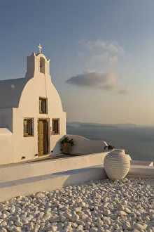 View of traditional white washed Church at sunset in Oia, Santorini, Greek Islands View of traditional white washed Church at sunset in Oia, Santorini, Greek Islands