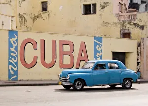 A vintage 1950s American car passing a Viva Cuba sign painted on a wall in cental Havana A vintage 1950s American car passing a Viva Cuba sign painted on a wall in cental Havana