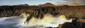 Volcanic coastline with waves crashing into sea caves, Los Hervideros Volcanic coastline with waves crashing into sea caves, Los Hervideros
