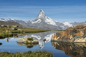 Contemplating Gallery: A walker hiking in the Alps takes in the view of the Matterhorn reflected in Stellisee