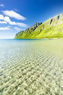 White sand washed by turquoise clear sea with mountains on background, Ersfjord beach White sand washed by turquoise clear sea with mountains on background, Ersfjord beach