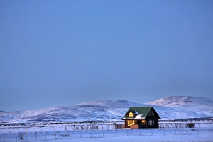 Winter landscape at dusk showing lone cabin bathed in evening sunlight Winter landscape at dusk showing lone cabin bathed in evening sunlight