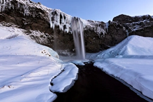 Winter view of Seljalandsfoss Waterfall at dusk with snow covered foreground Winter view of Seljalandsfoss Waterfall at dusk with snow covered foreground