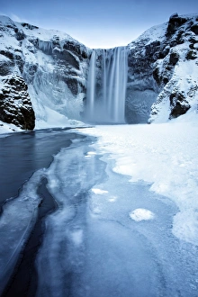 Winter view of Skogafoss waterfall, with cliffs covered in icicles Winter view of Skogafoss waterfall, with cliffs covered in icicles
