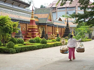 Cambodian Culture Collection: Woman carrying baskets over her shoulders outside a temple in Siem Reap, Cambodia