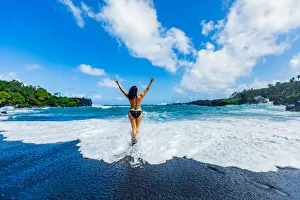 Woman enjoying the sun on one of Maui's black sand beaches, Maui, Hawaii Woman enjoying the sun on one of Maui's black sand beaches, Maui, Hawaii