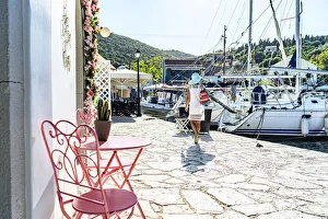 Woman looking at sailboats in the small harbor of the coastal village of Fiskardo, Kefalonia, Ionian Islands Woman looking at sailboats in the small harbor of the coastal village of Fiskardo, Kefalonia, Ionian Islands
