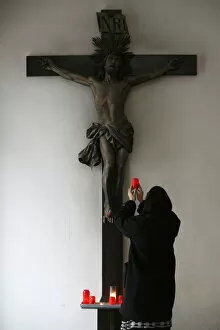 Images Dated 28th September 2009: Woman offering candle and praying in front of Crucifix