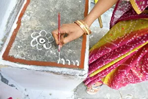 Decorations Collection: Woman painting her doorstep with rice flour paste, making rangoli design Diwali Festival