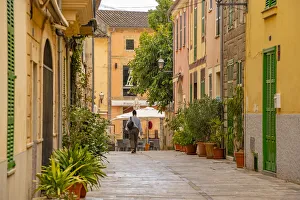 Woman walking down narrow street in the old town of Alcudia, Alcudia, Majorca, Balearic Islands, Spain, Mediterranean Woman walking down narrow street in the old town of Alcudia, Alcudia, Majorca, Balearic Islands, Spain, Mediterranean
