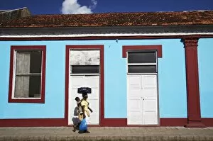 Woman walking past colourful house, Inhambane, Mozambique, Africa