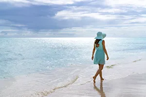 Woman walking on a white sand beach under the cloudy sky at sunset, Barbuda, Antigua and Barbuda, West Indies Woman walking on a white sand beach under the cloudy sky at sunset, Barbuda, Antigua and Barbuda, West Indies