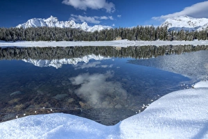Wooden chalet surrounded by snowy peaks and woods reflected in Lake Palu, Malenco Valley Wooden chalet surrounded by snowy peaks and woods reflected in Lake Palu, Malenco Valley