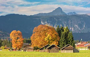 Wooden huts surrounded by colorful trees in autumn, Garmisch Partenkirchen, Upper Bavaria Wooden huts surrounded by colorful trees in autumn, Garmisch Partenkirchen, Upper Bavaria