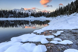 Woods and snowy peaks are reflected in Lake Palu at sunrise, Malenco Valley, Valtellina